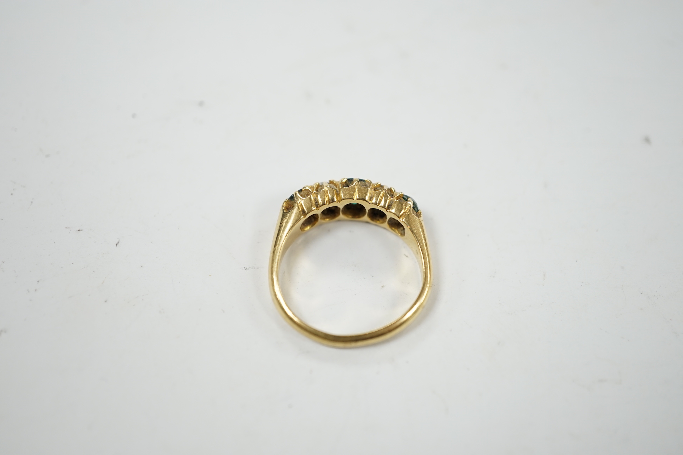 An early 20th century 18ct, three stone green garnet and two stone diamond claw set half hoop ring, size L, gross weight 4.8 grams.